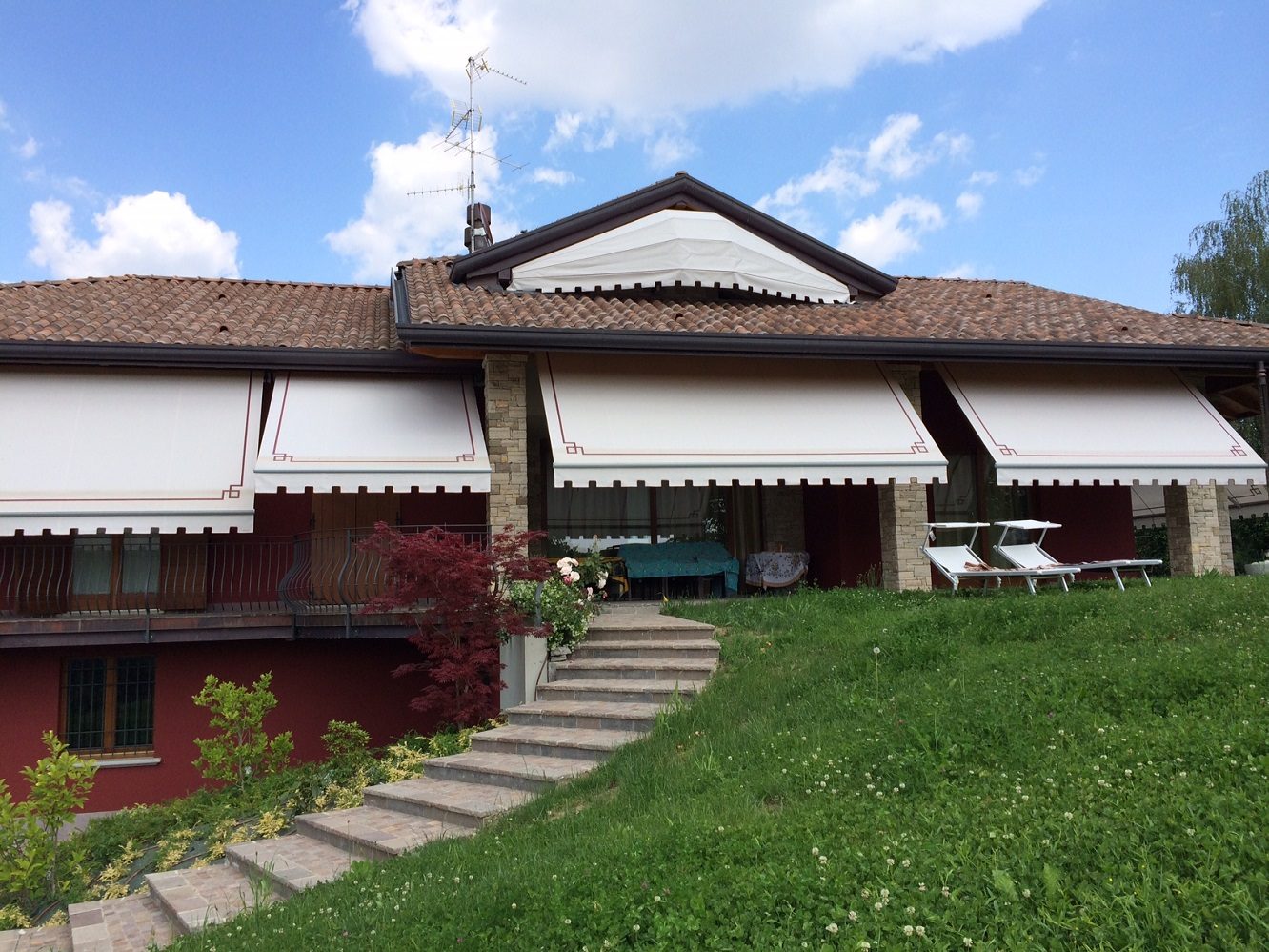 Villa con quattro tende a bracci estensibili aperte lungo la facciata