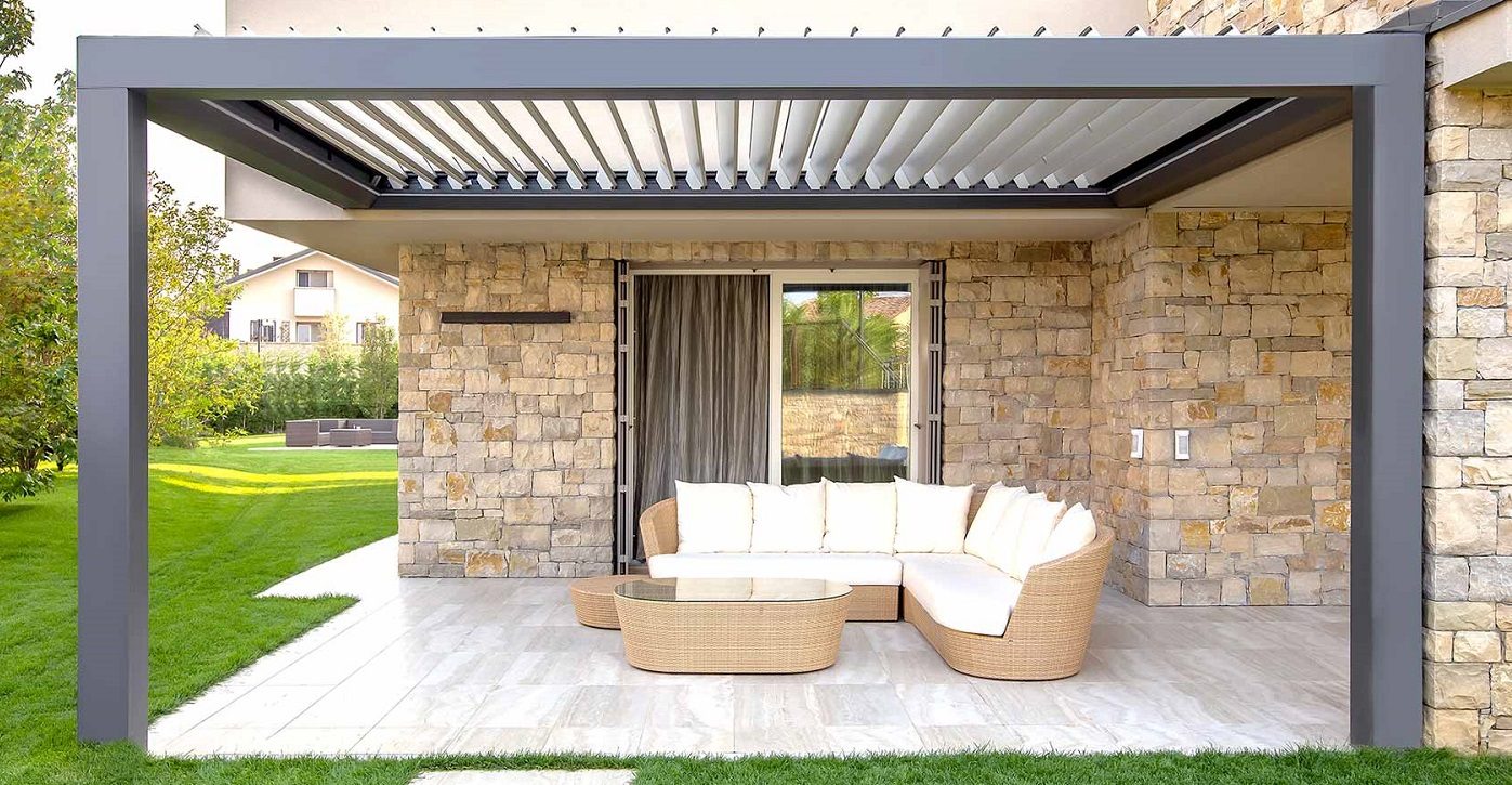 Pergola in alluminio con lame orientabili sopra un salotto da giardino