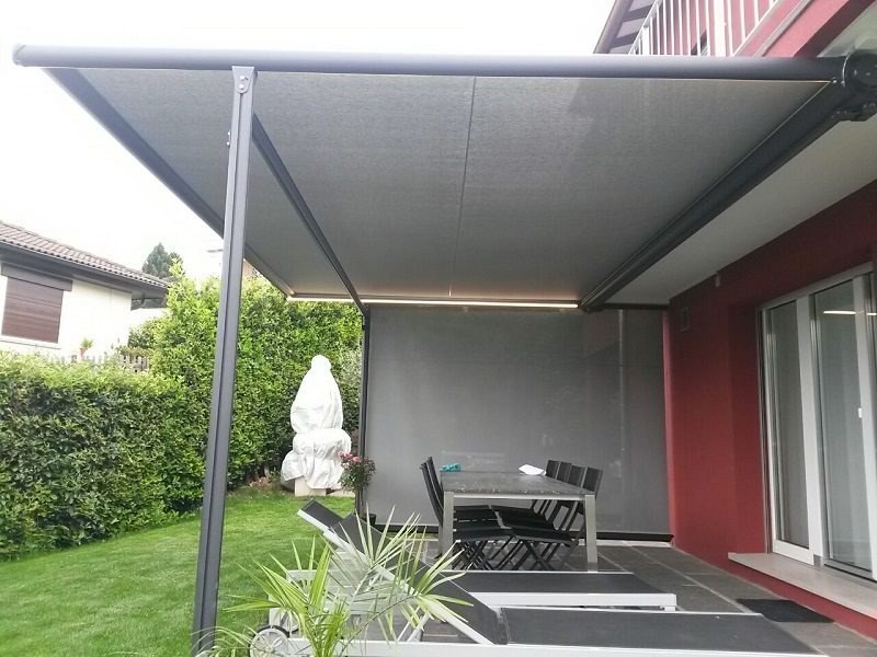 Terrazzo con tenda a bracci grigia e chiusure laterali verticali in tessuto